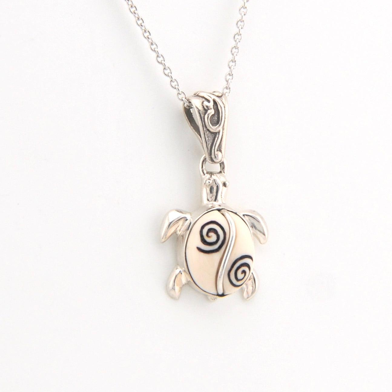 Silver turtle pendant necklace on a white background