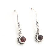 Pair of silver earrings with dark gemstones on a white background