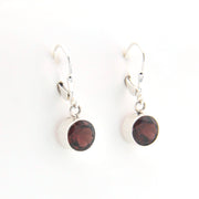 Silver earrings with red gemstones on a white background