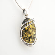 Silver pendant with a large amber stone on a white background
