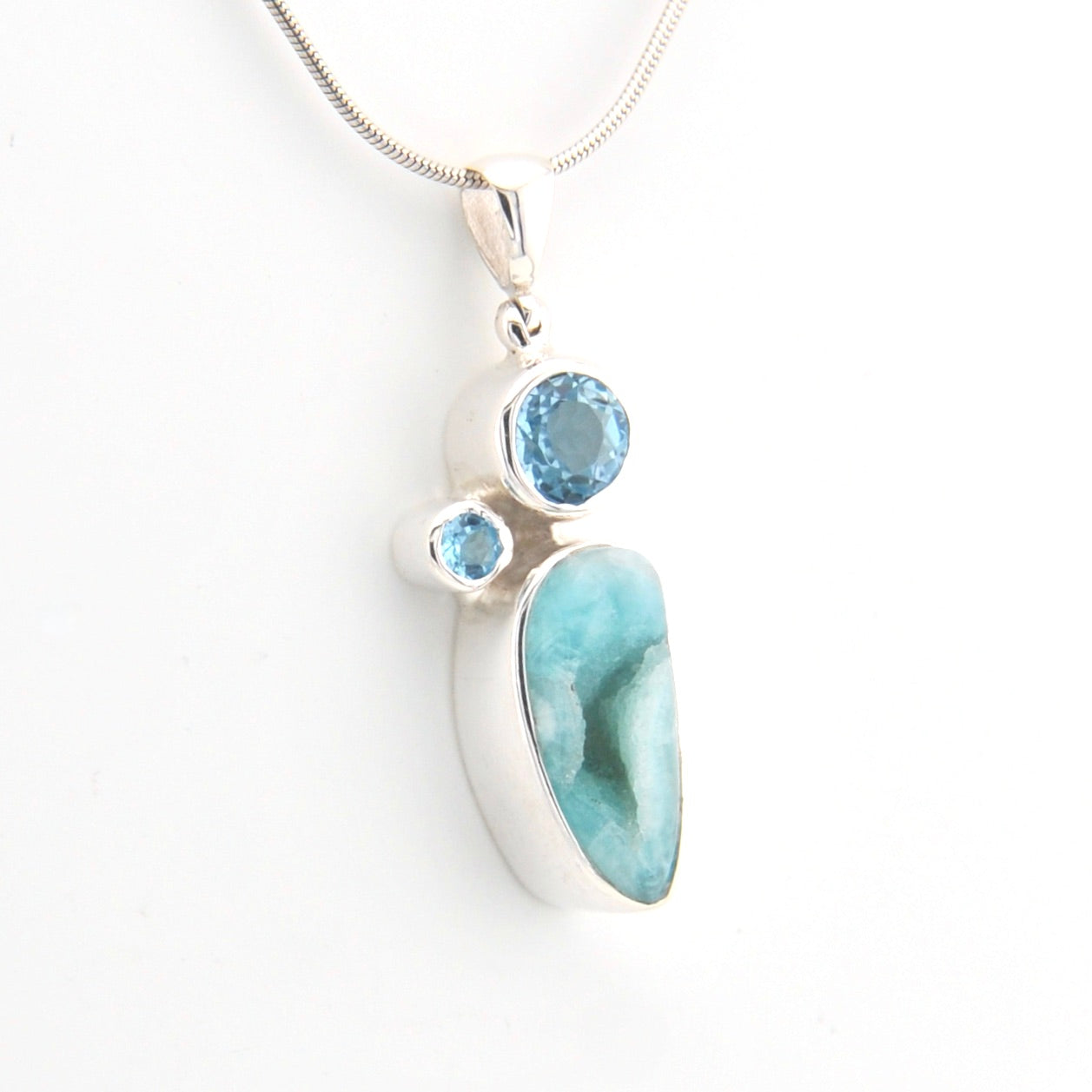 Hemimorphite pendant with blue topaz stones on a white background