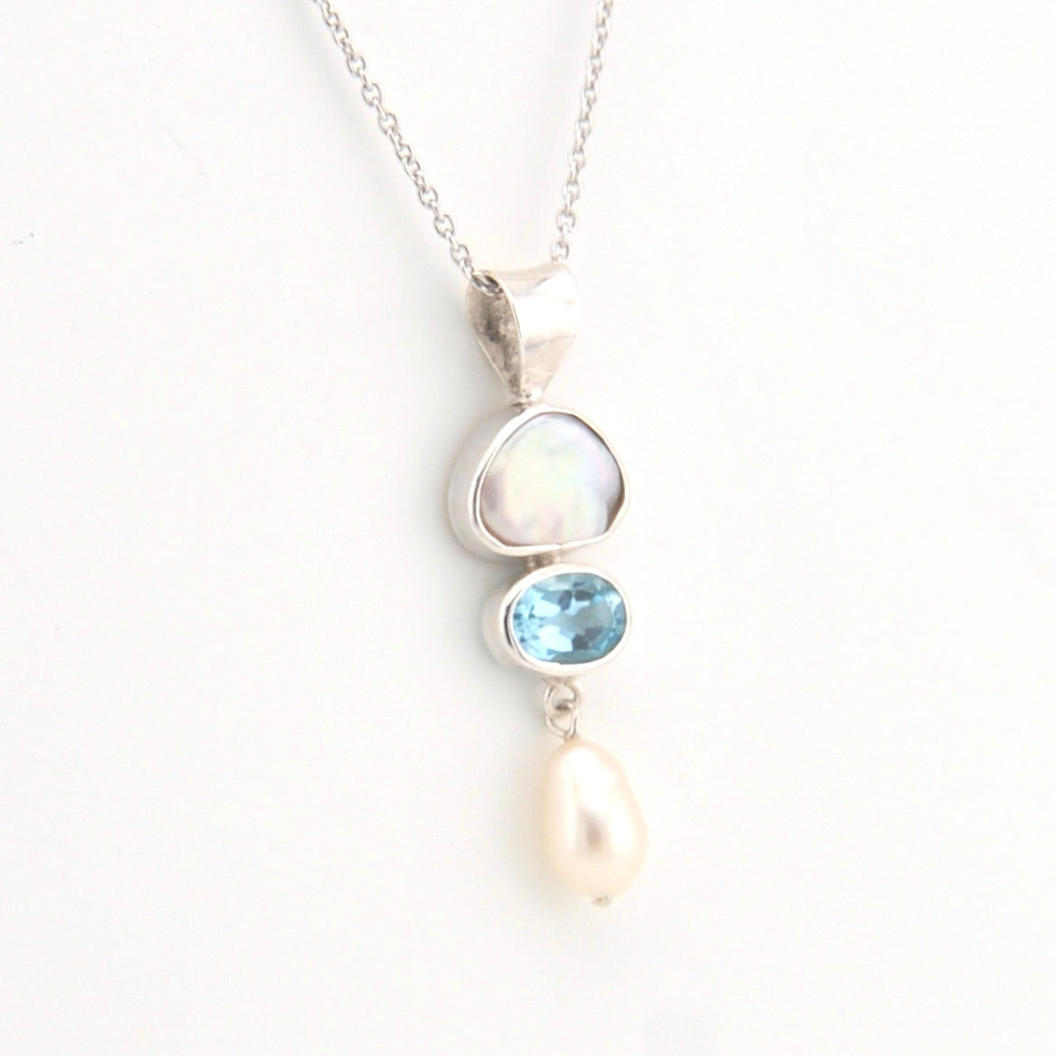 Necklace with a pendant featuring pearls and a blue gemstone on a white background