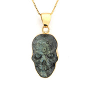 Skull-shaped pendant with gold frame on a white background