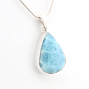 Teardrop-shaped larimar pendant on a silver chain against a white background