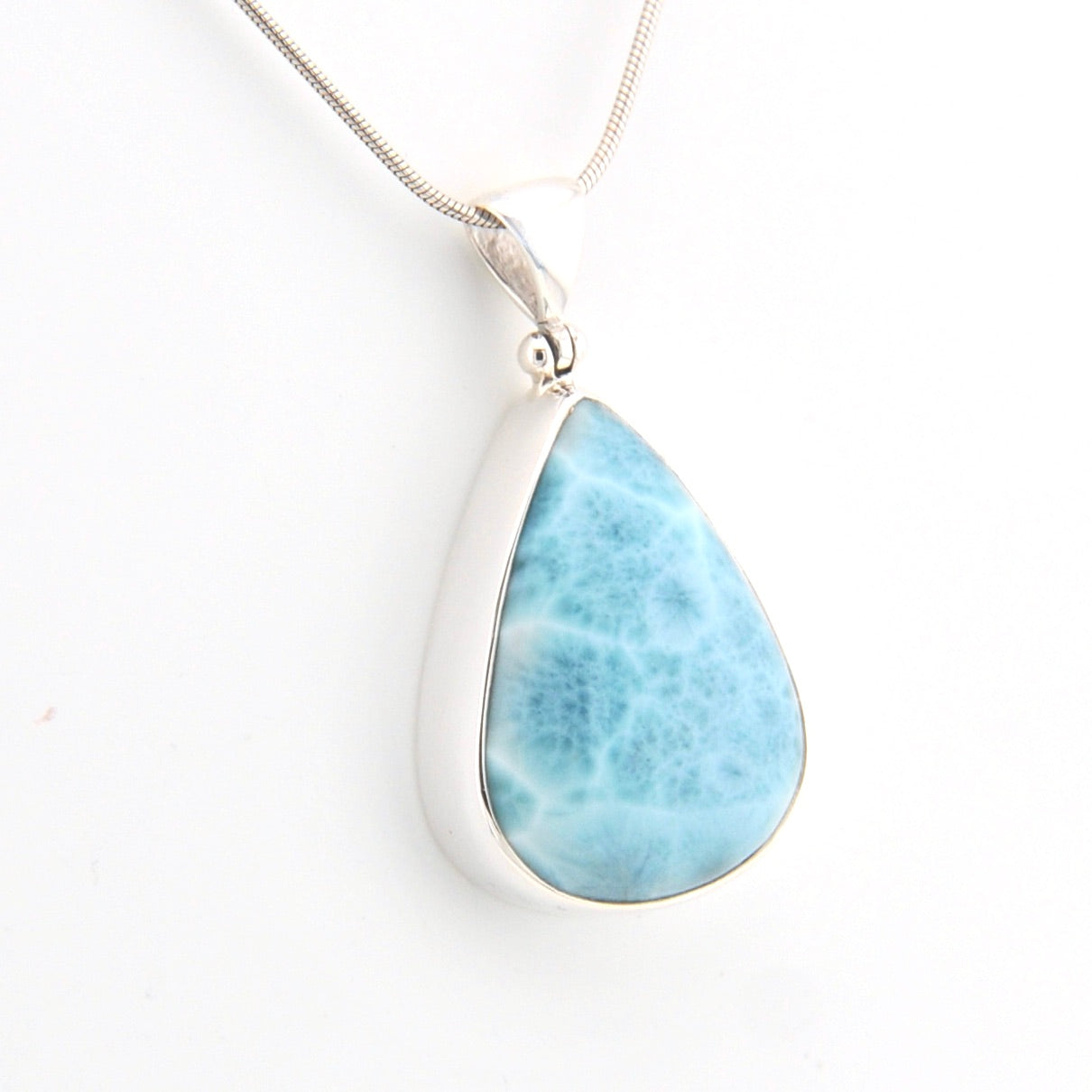 Teardrop-shaped larimar pendant on a silver chain against a white background