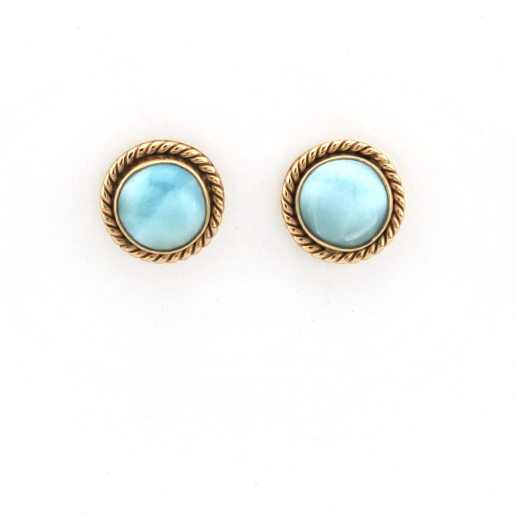 Pair of earrings with gold rims and light blue gemstones on a white background