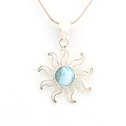 Silver sun-shaped pendant with a blue stone on a white background