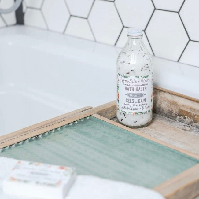 Bottle of bath salts on a wooden tray with a tiled wall background