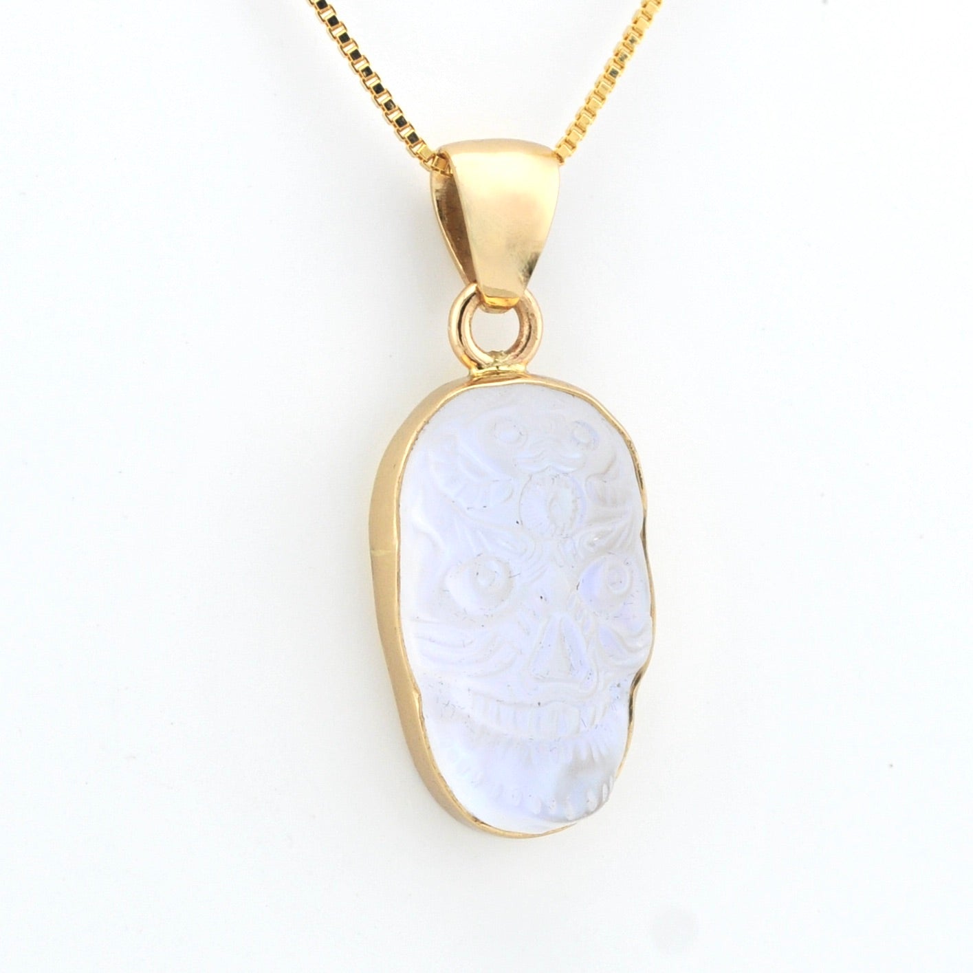 Gold pendant with a white stone on a white background