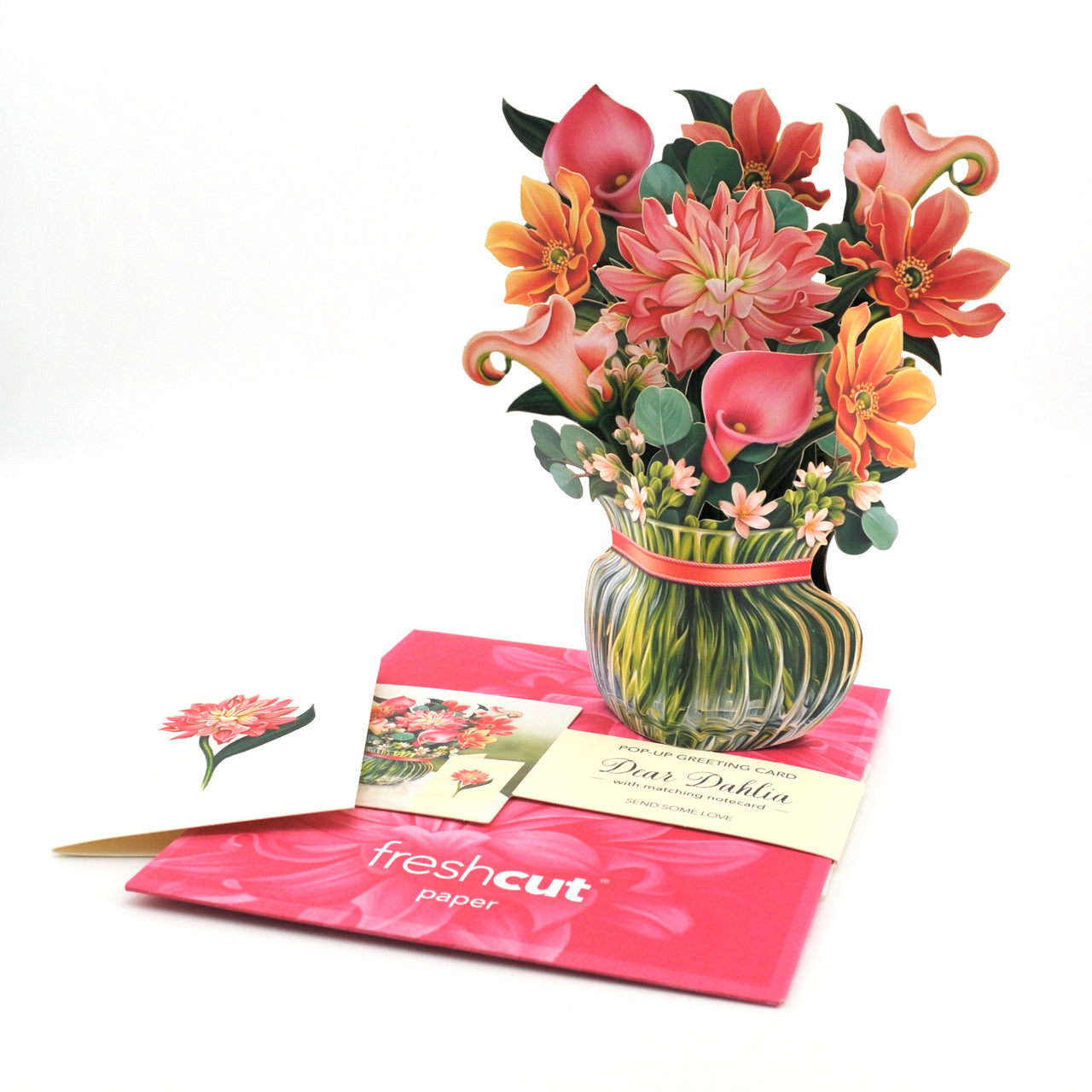 Bouquet of flowers in a glass vase with a pink ribbon, placed on a pink card with 'fresh cut paper' branding.
