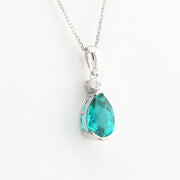 Teardrop-shaped green gemstone pendant on a silver chain against a white background