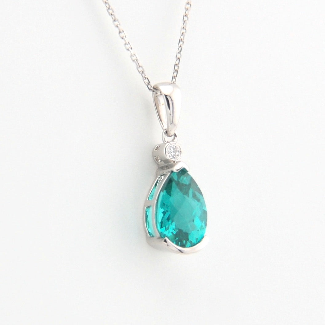 Teardrop-shaped green gemstone pendant on a silver chain against a white background