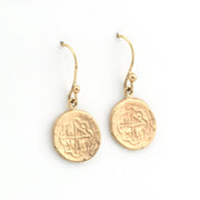 Gold coin-shaped earrings on a white background