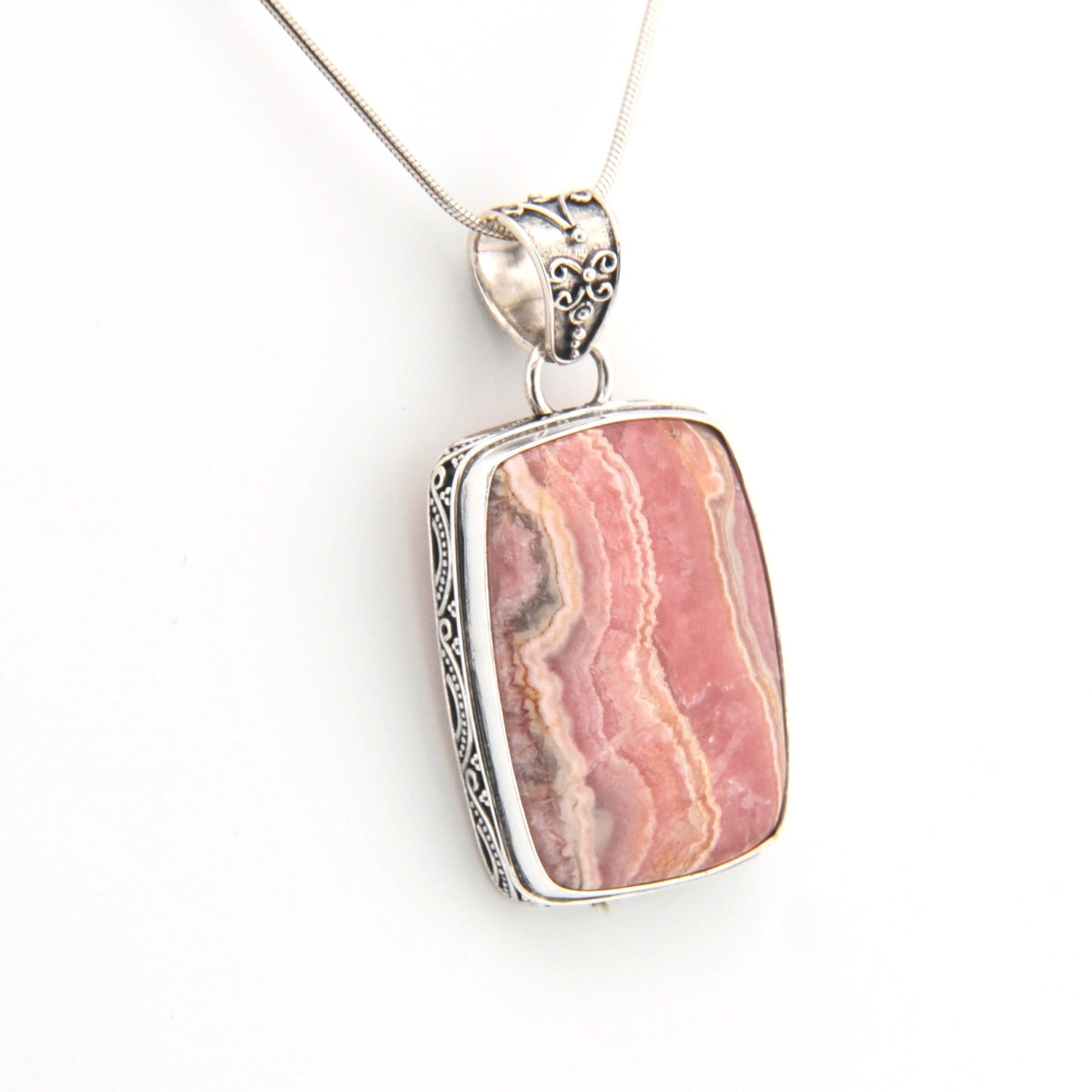 Pink stone pendant with silver frame on a white background