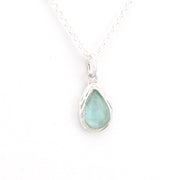 Teardrop-shaped pendant with a light blue Roman glass on a white background