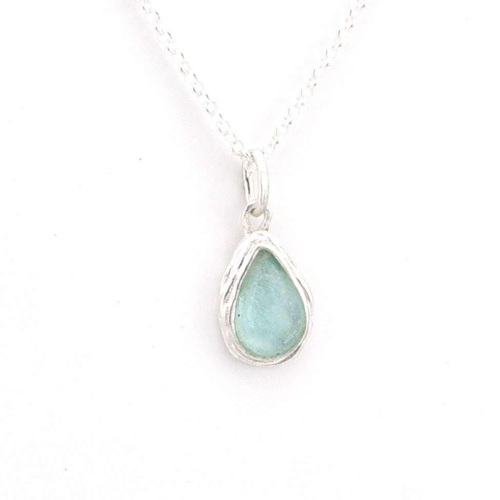 Teardrop-shaped pendant with a light blue Roman glass on a white background