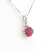 Silver necklace with a red gemstone pendant on a white background