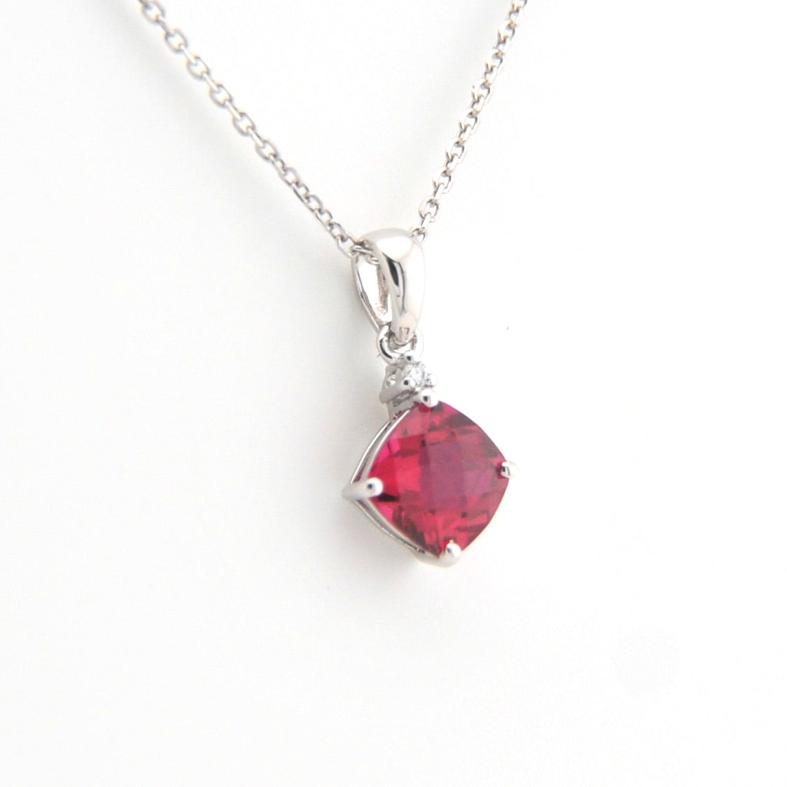 Silver necklace with a red gemstone pendant on a white background