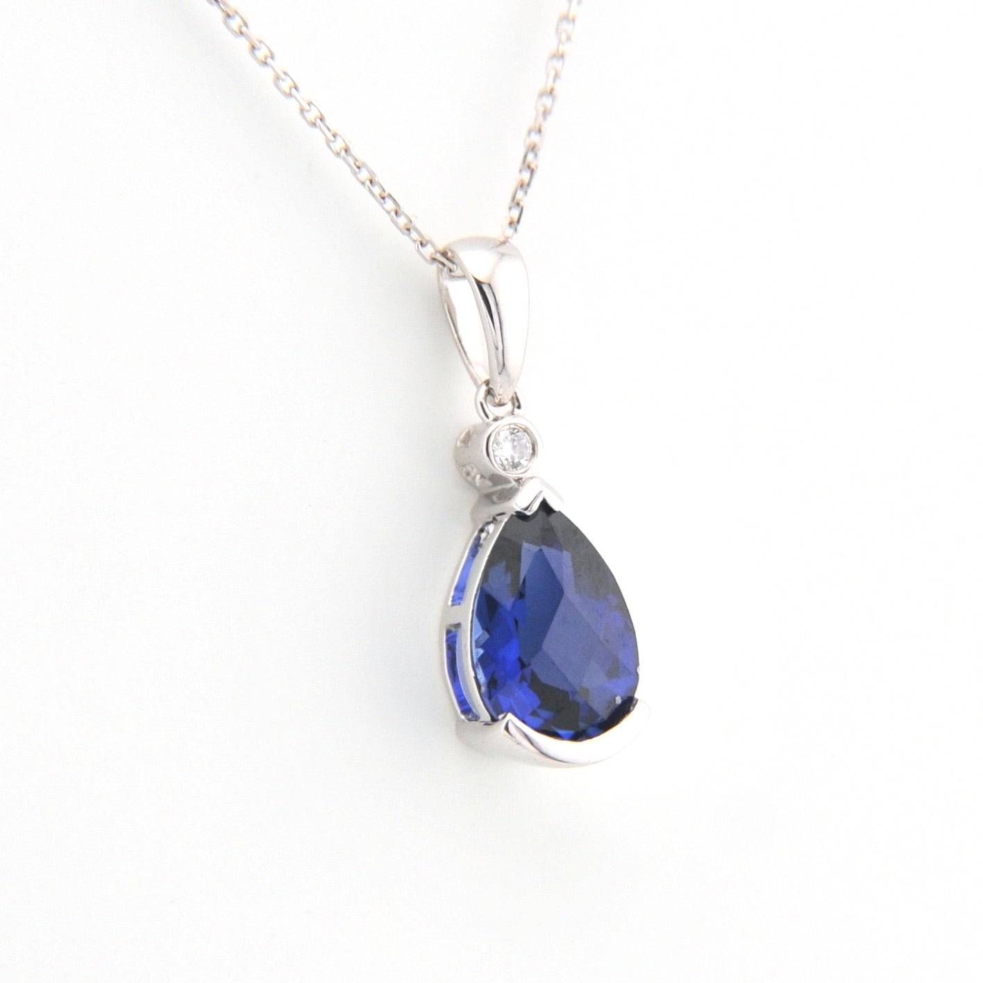 Teardrop-shaped blue gemstone pendant on a white background