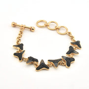 Gold bracelet with black butterfly-shaped charms on a white background