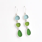A pair of silver drop earrings featuring three stacked sea glass stones in light blue, green, and teal, shown against a plain white background.