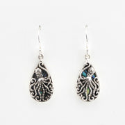 Pair of silver teardrop earrings with intricate designs on a white background