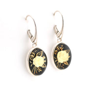 Pair of earrings with black and gold floral designs on a white background