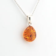 Teardrop-shaped amber pendant on a silver chain against a white background