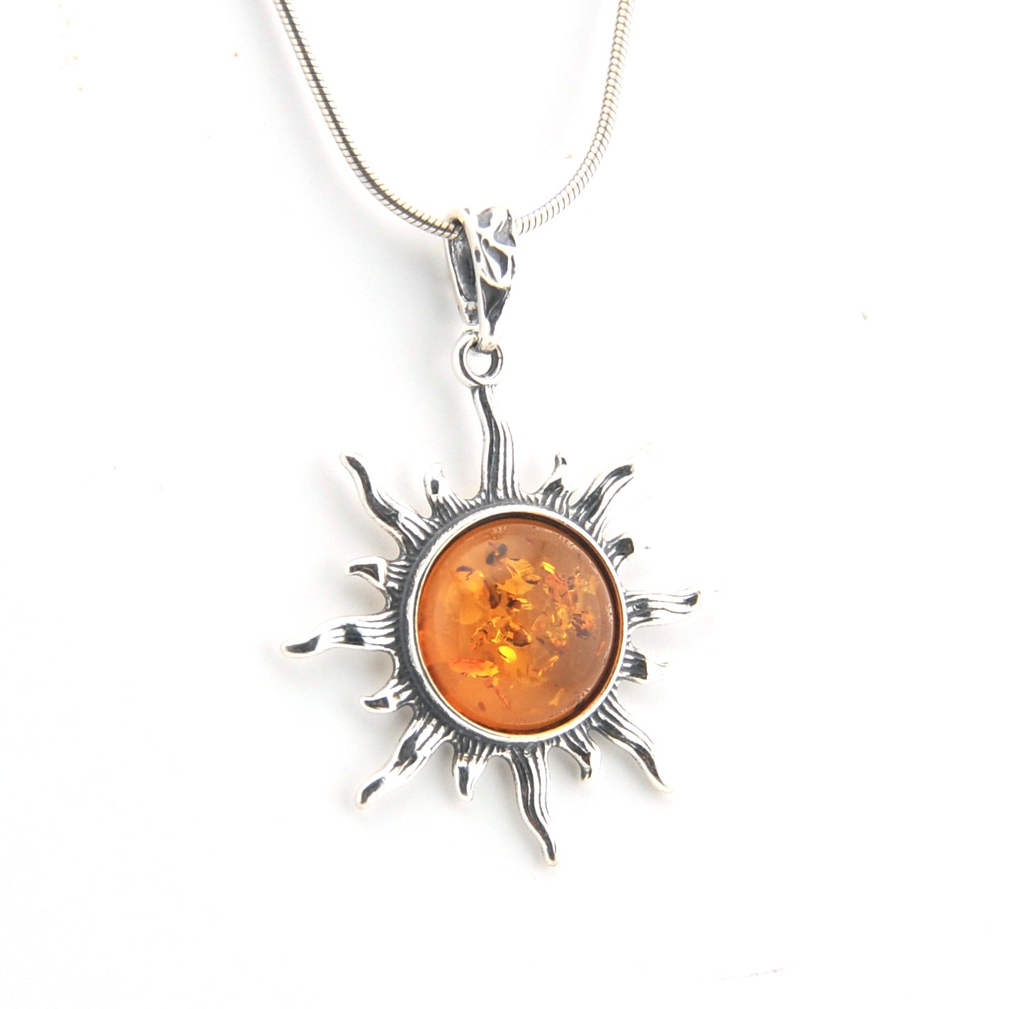 Silver sun-shaped pendant with amber center on a white background