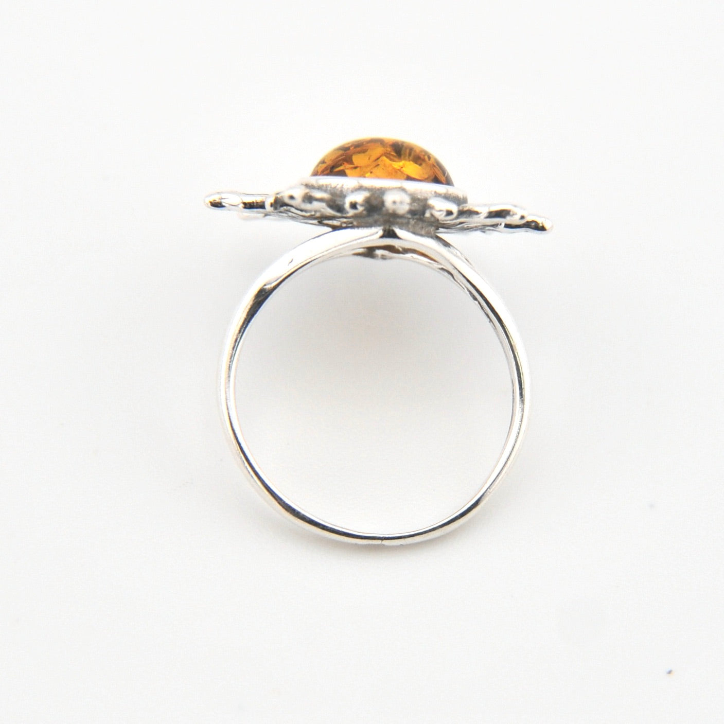 Silver ring with a yellow gemstone on a white background