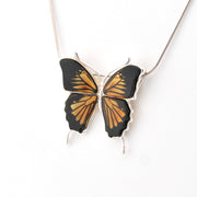 Butterfly-shaped pendant on a chain against a white background