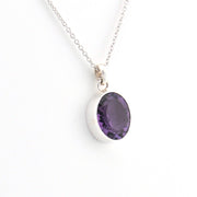 Silver necklace with a purple gemstone pendant on a white background
