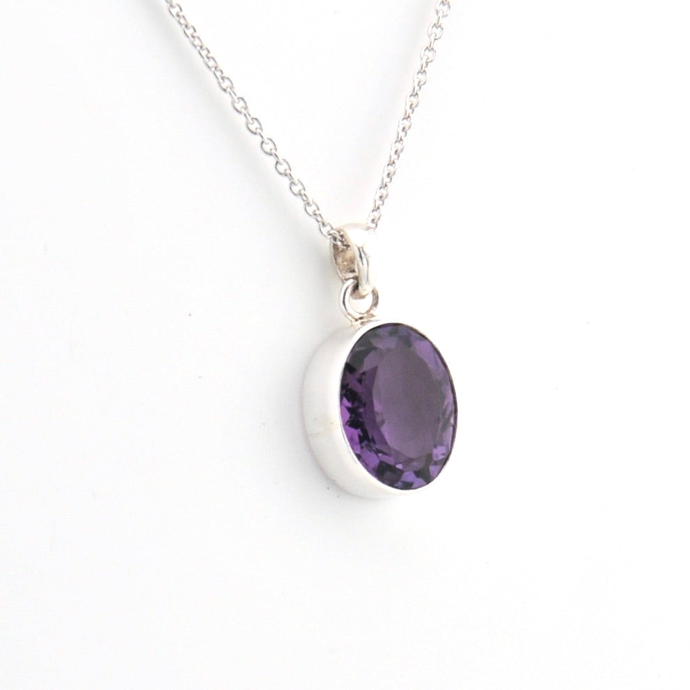 Silver necklace with a purple gemstone pendant on a white background