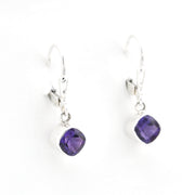 Pair of silver earrings with purple gemstones on a white background
