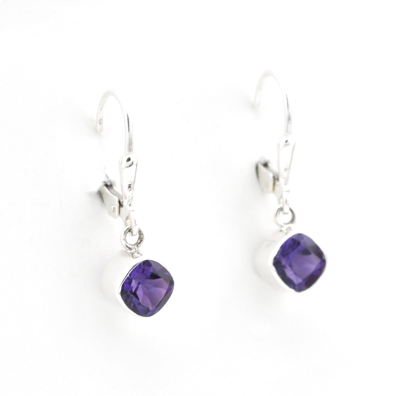 Pair of silver earrings with purple gemstones on a white background