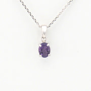 Purple gemstone pendant on a silver chain against a white background