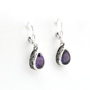 Pair of silver earrings with purple gemstones on a white background
