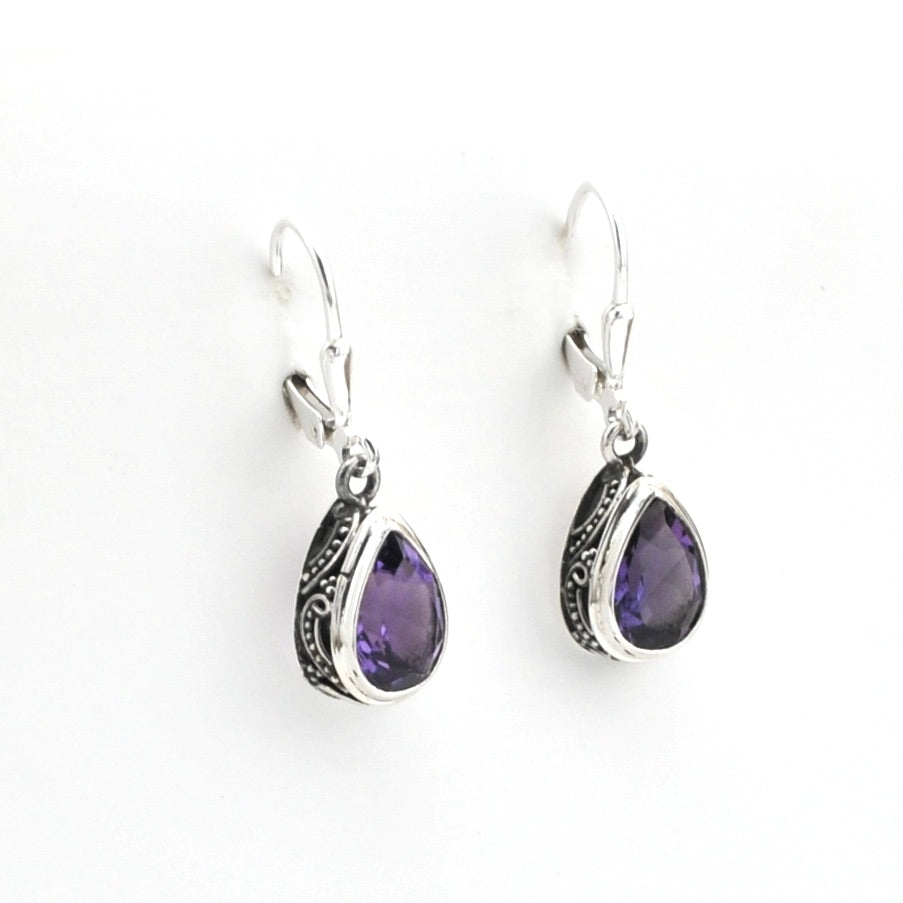 Pair of silver earrings with purple gemstones on a white background