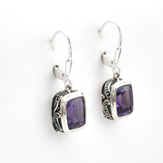 Silver earrings with purple gemstones on a white background