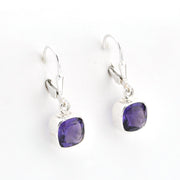 Purple gemstone earrings on silver hooks against a white background