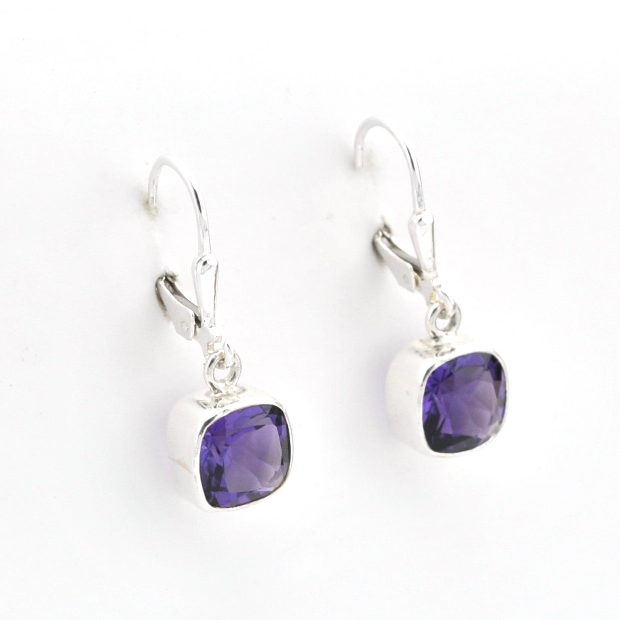 Purple gemstone earrings on silver hooks against a white background