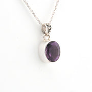 Silver necklace with a purple gemstone pendant on a white background