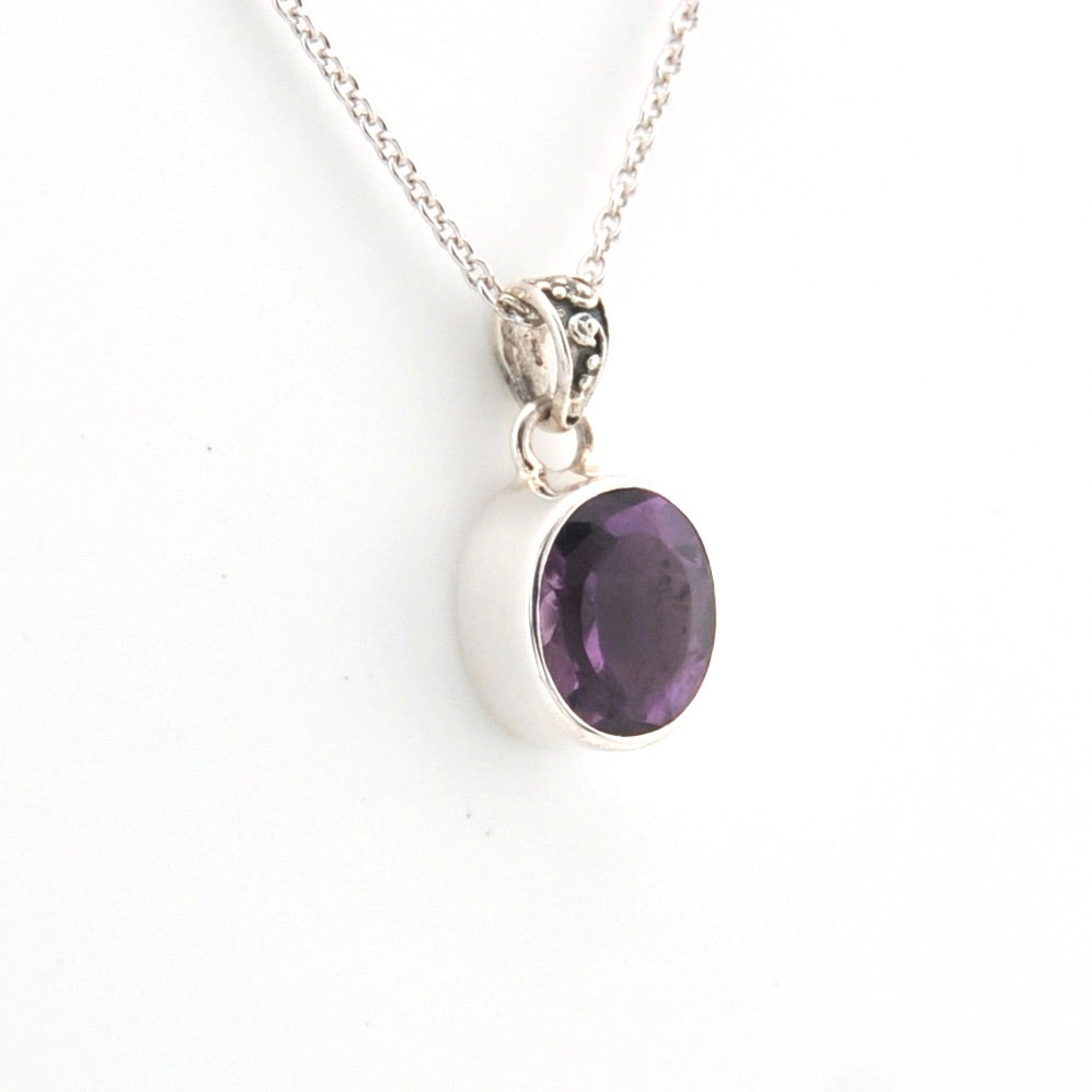 Silver necklace with a purple gemstone pendant on a white background