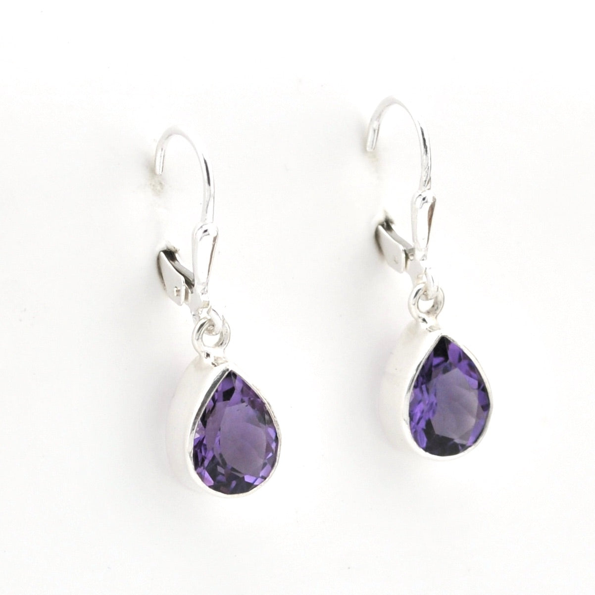 Pair of silver earrings with purple teardrop-shaped gemstones on a white background