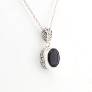 Silver pendant with a black stone on a white background