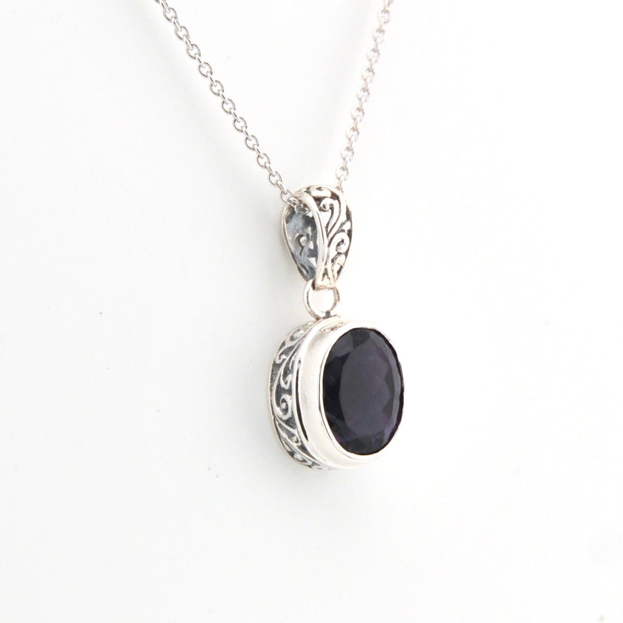 Silver pendant with a black stone on a white background