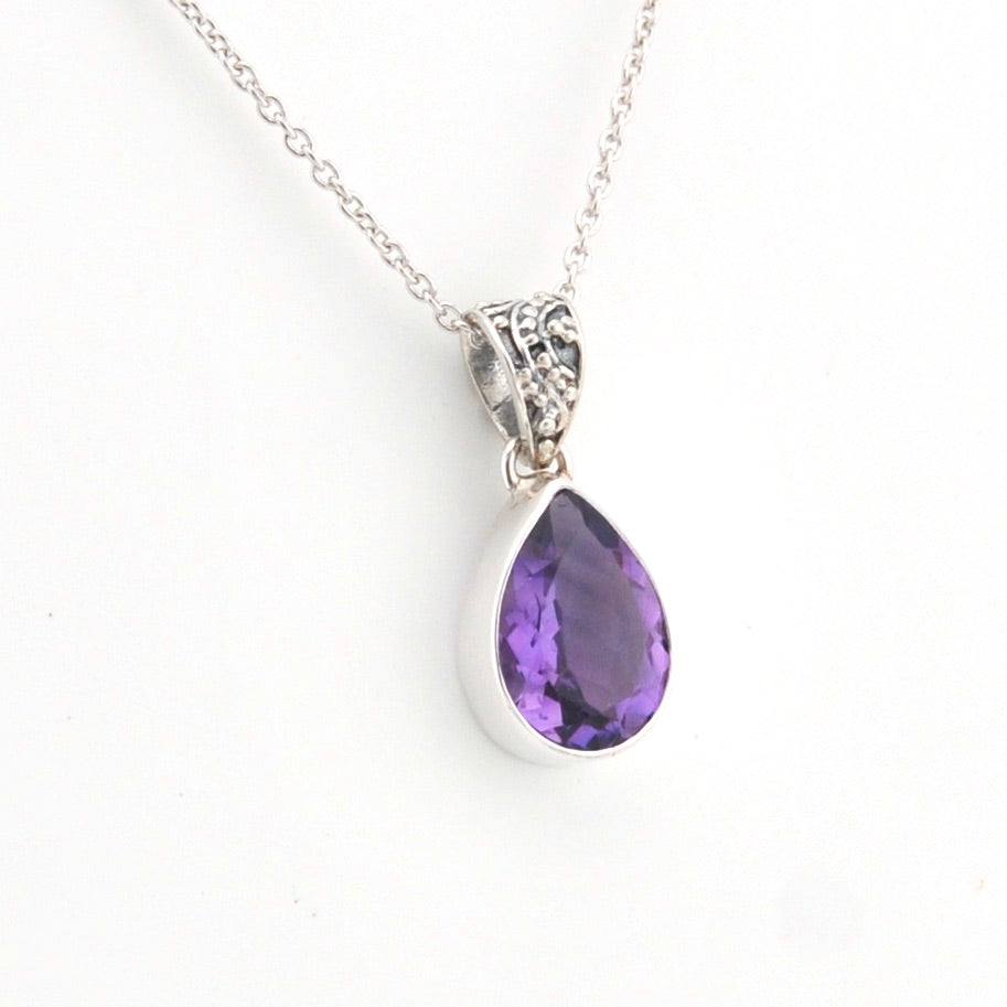 Purple teardrop pendant on a silver chain against a white background
