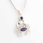 Silver crab pendant with purple gemstones on a white background