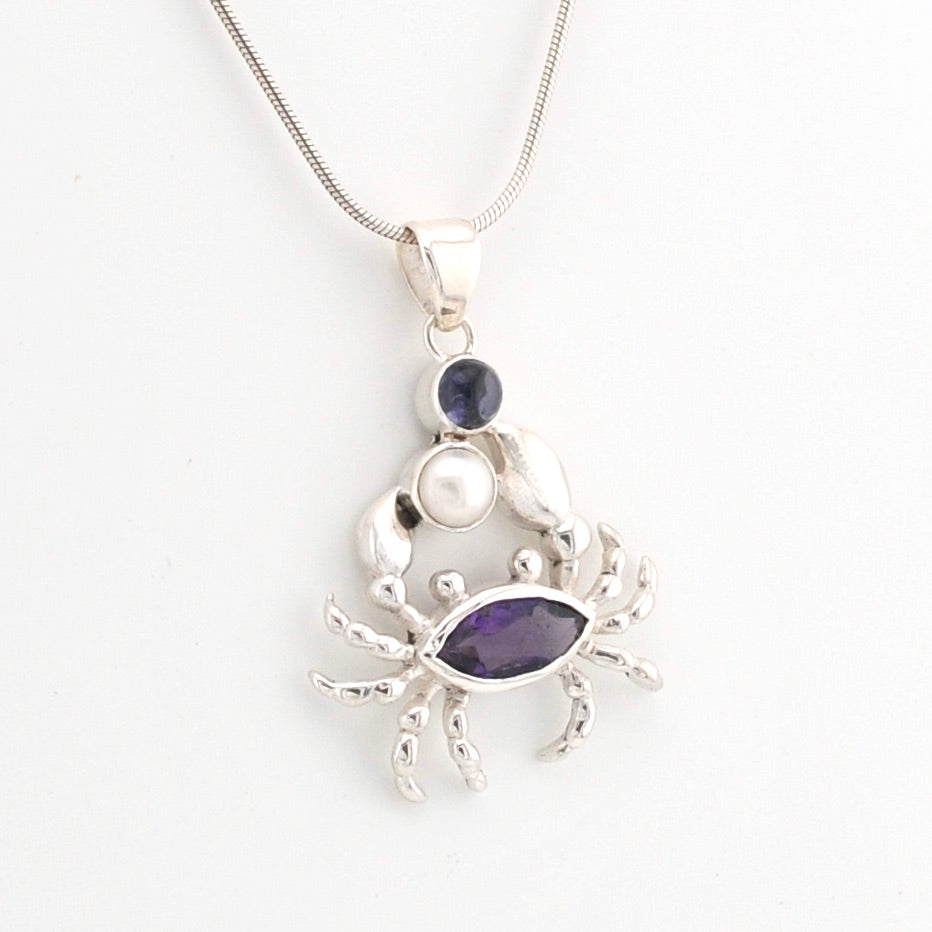 Silver crab pendant with purple gemstones on a white background