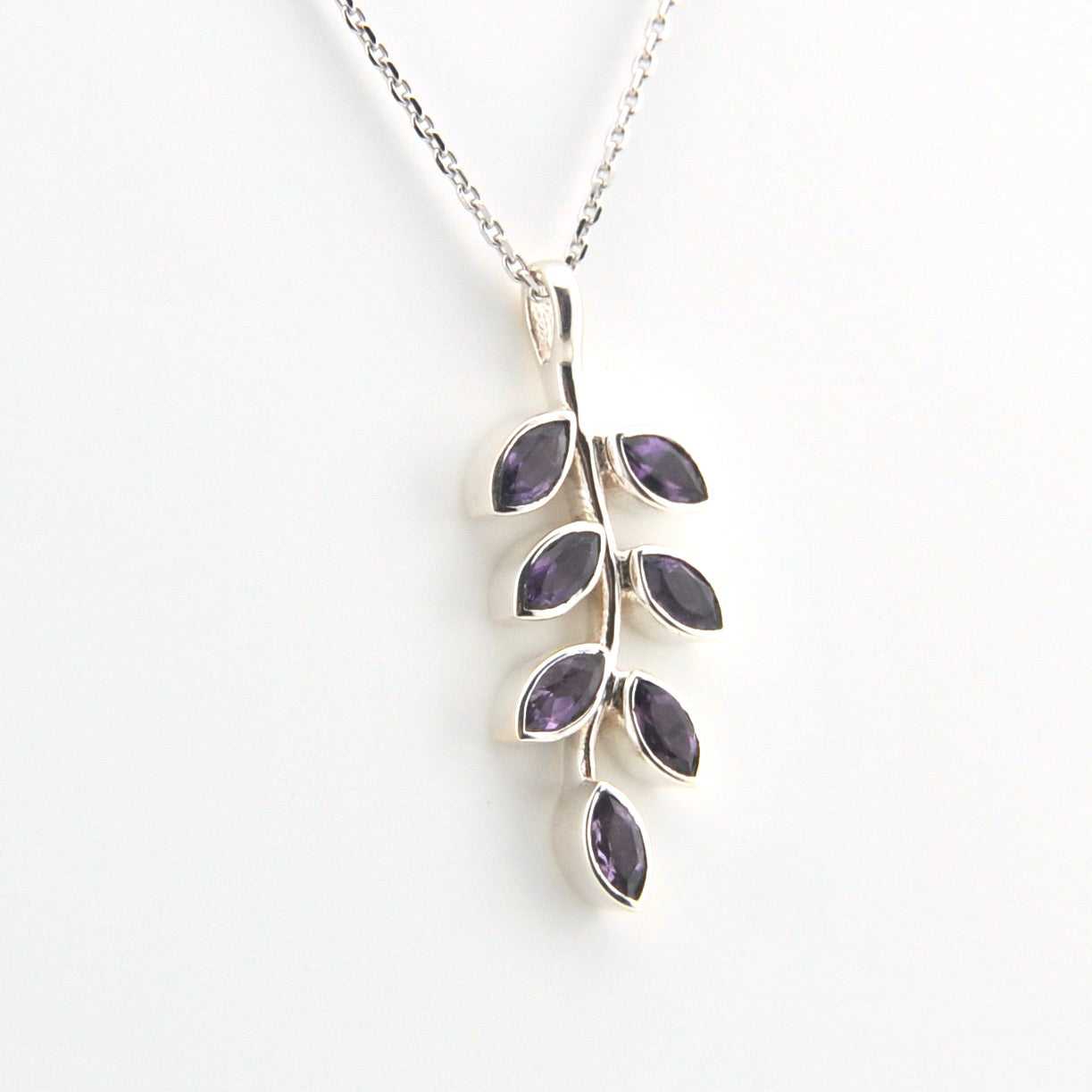 Silver necklace with purple gemstone leaves on a white background